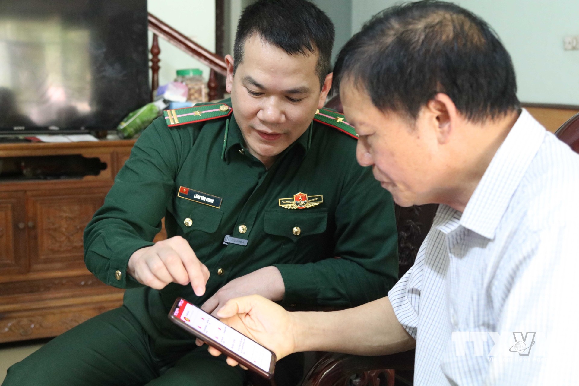 Cán bộ Đồn Biên phòng cửa khẩu Chi Ma hướng dẫn người dân xã Mẫu Sơn sử dụng các ứng dụng số trên điện thoại thông minh. (Ảnh: Quang Duy/TTXVN)